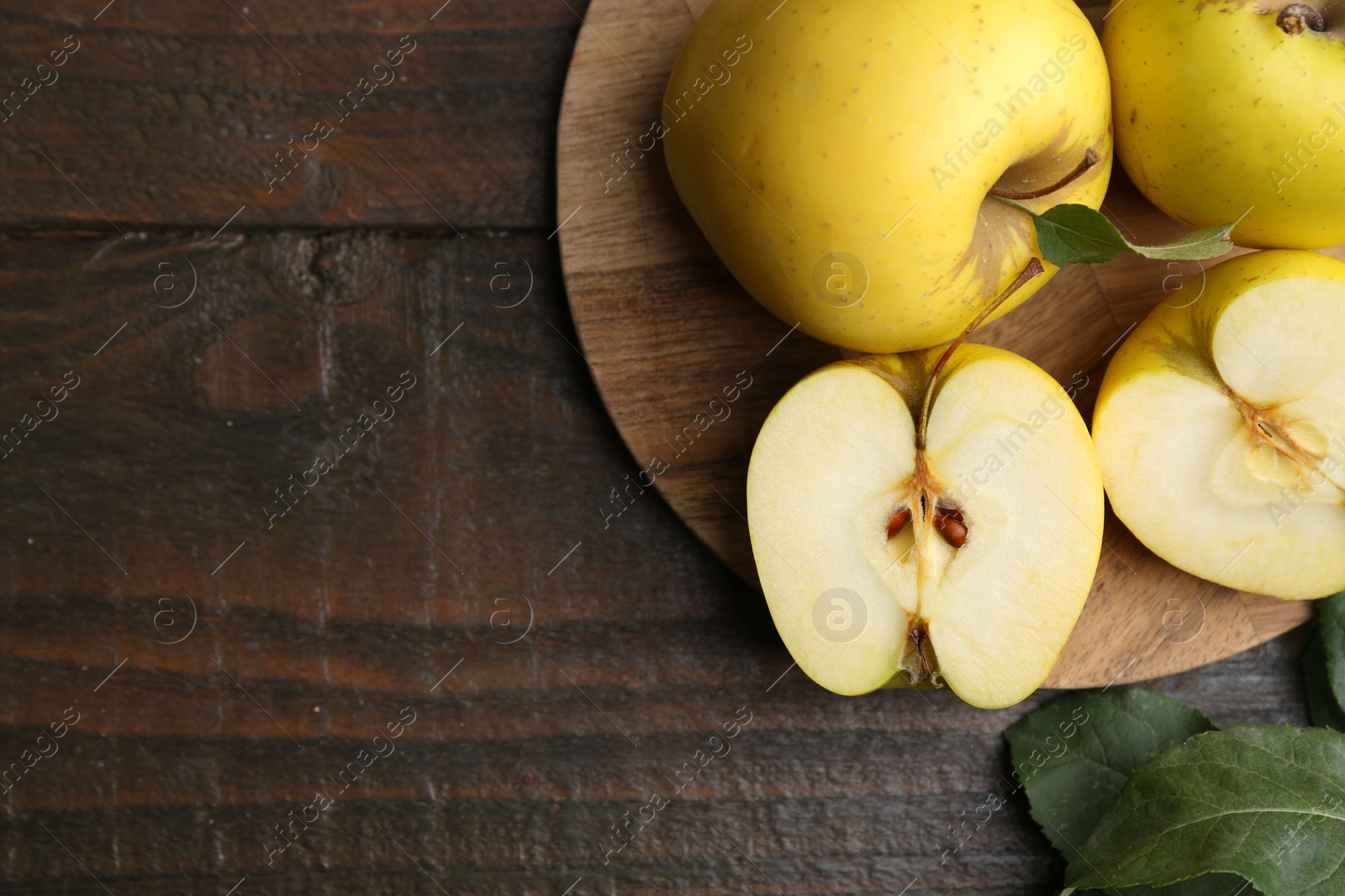 Photo of Fresh ripe yellow apples and green leaves on wooden table, flat lay. Space for text