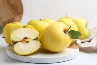 Photo of Fresh ripe yellow apples on white tiled table, closeup