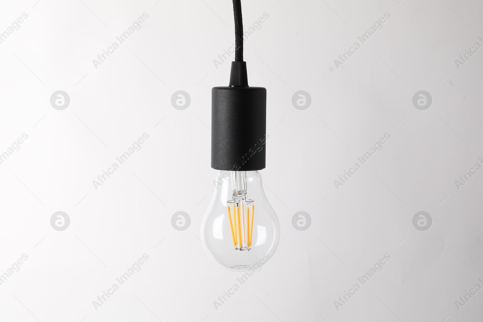 Photo of One light bulb hanging on cord against white background