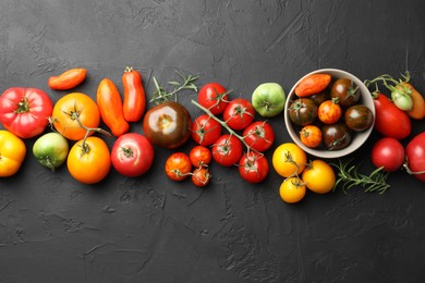 Photo of Different fresh tomatoes and rosemary on grey textured table, flat lay