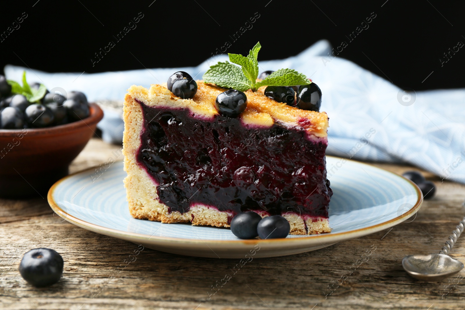 Photo of Slice of homemade blueberry pie on wooden table, closeup