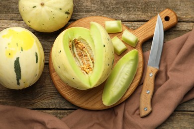 Photo of Fresh whole and cut honeydew melons on wooden table, flat lay