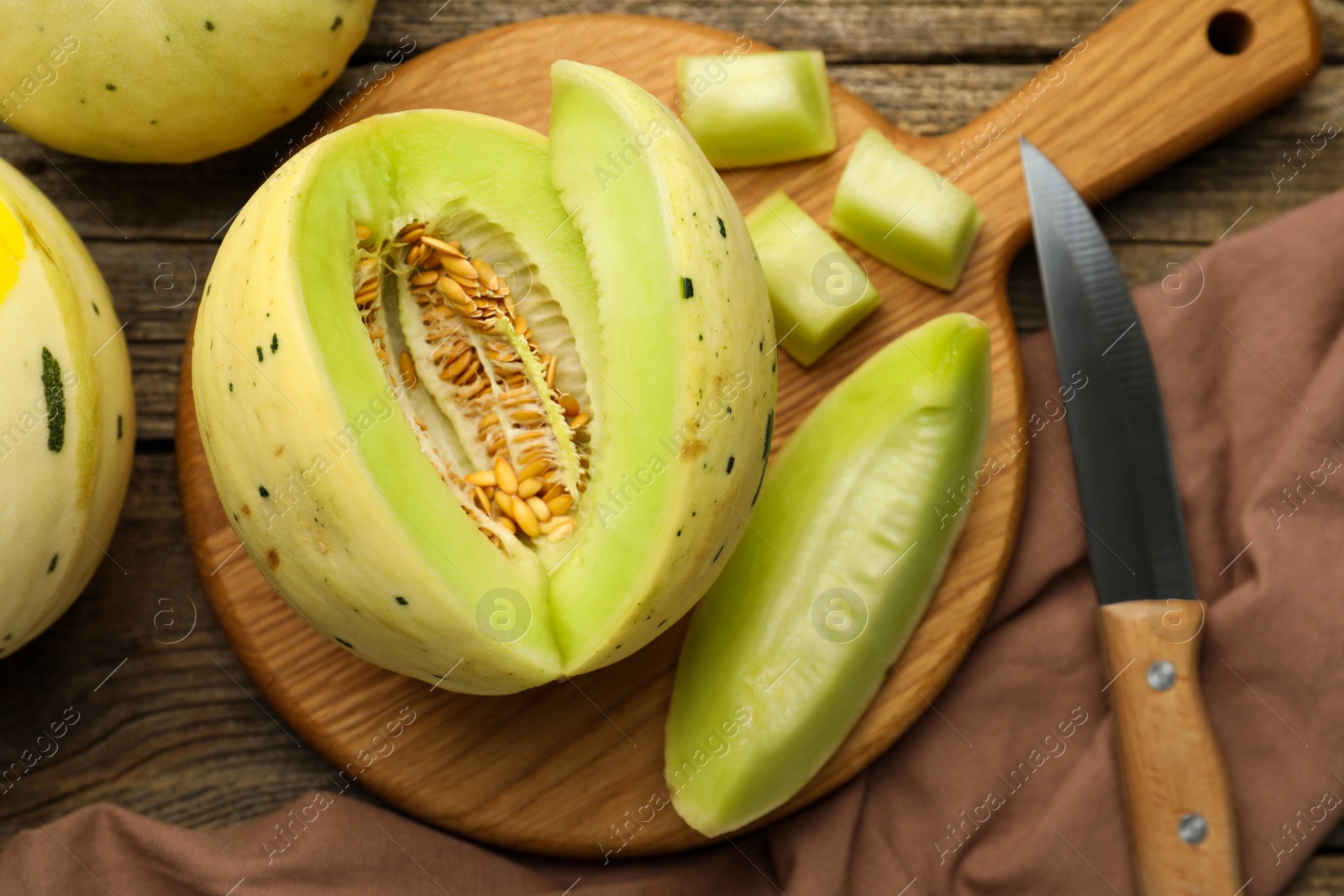 Photo of Fresh whole and cut honeydew melons on wooden table, flat lay