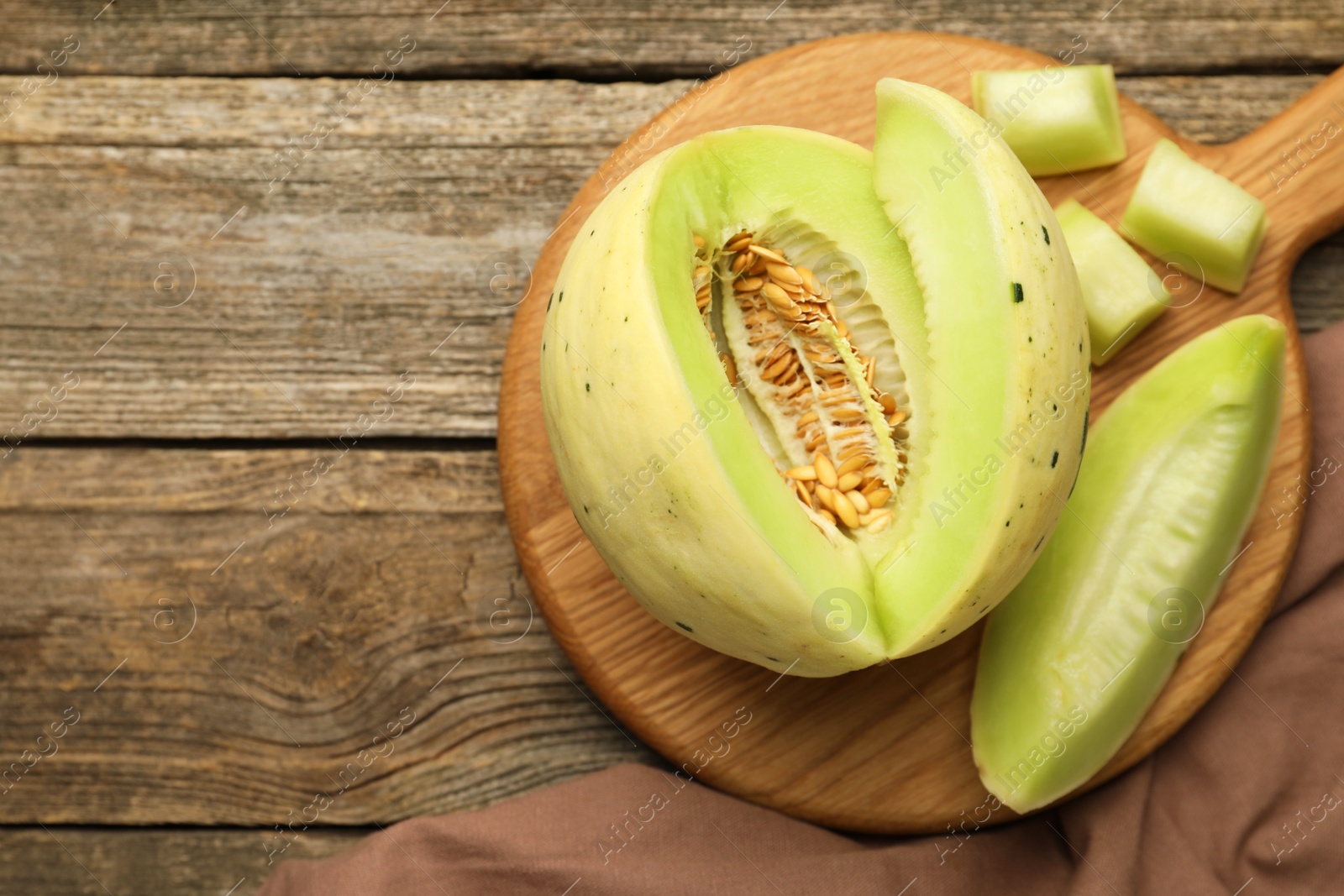 Photo of Fresh cut honeydew melon on wooden table, top view. Space for text