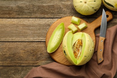 Photo of Fresh cut honeydew melon on wooden table, flat lay. Space for text