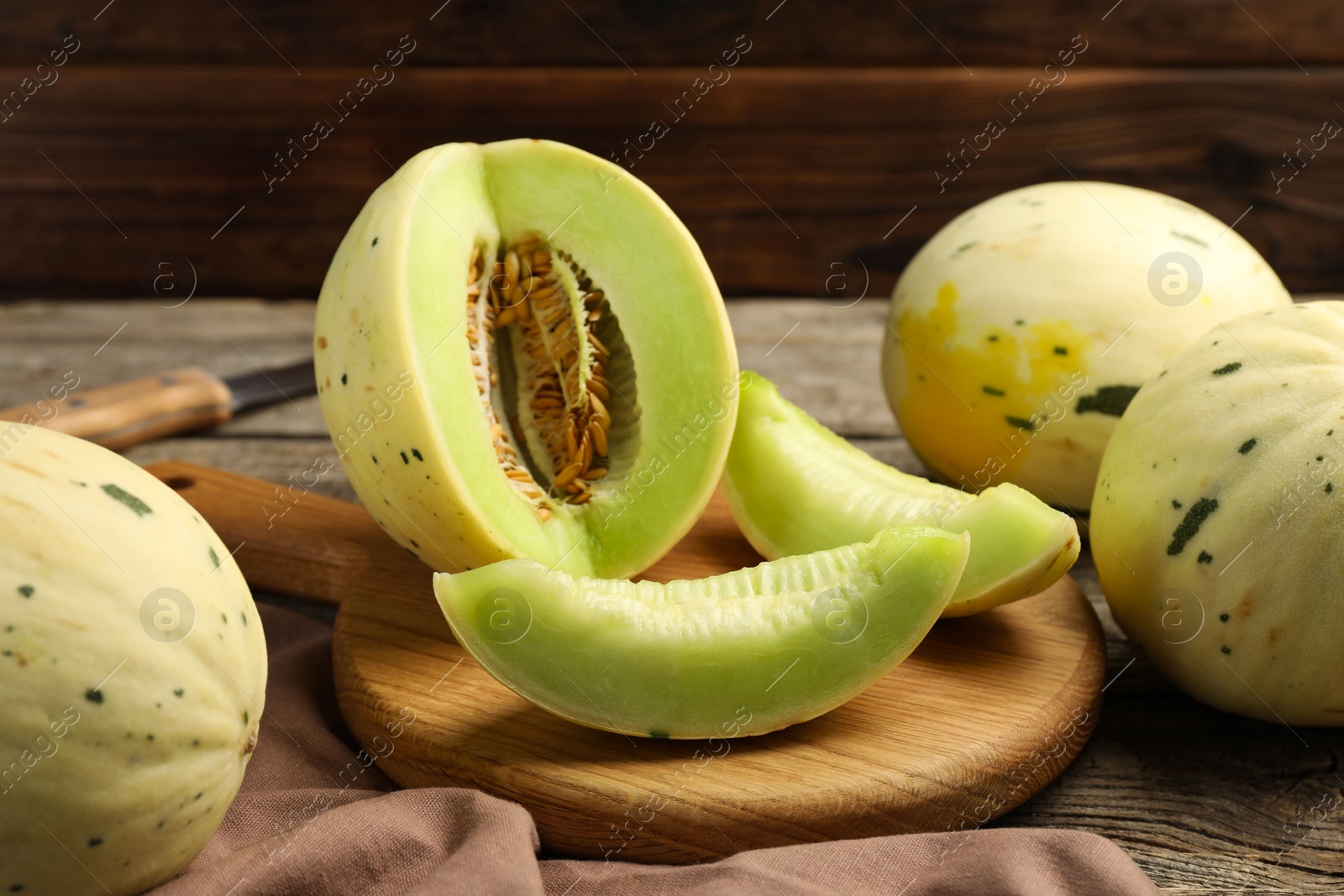 Photo of Fresh whole and cut honeydew melons on wooden table, closeup