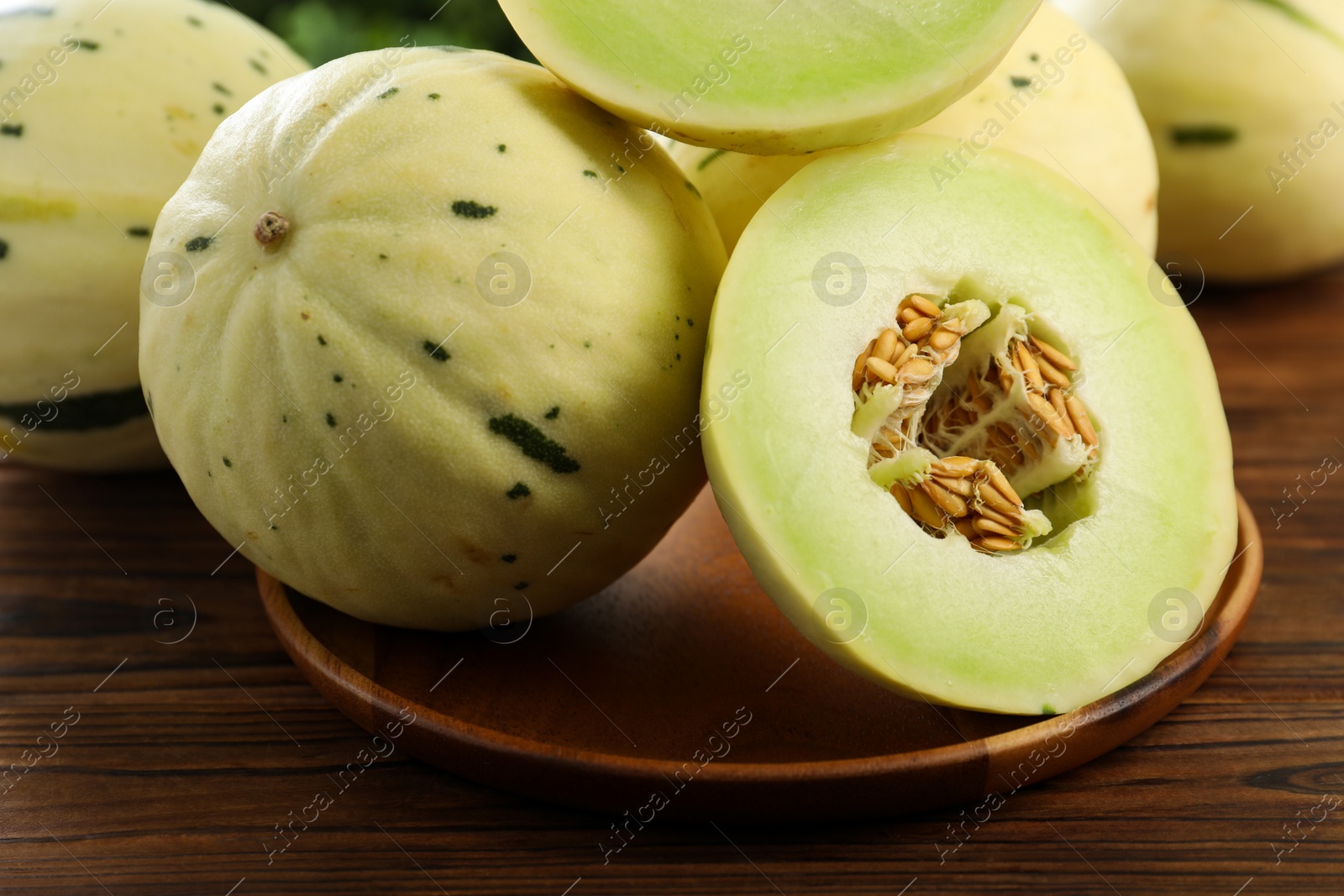 Photo of Fresh whole and cut honeydew melons on wooden table, closeup