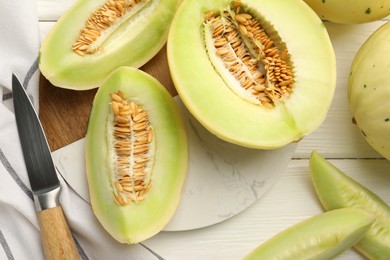 Photo of Fresh cut honeydew melons on white wooden table, flat lay