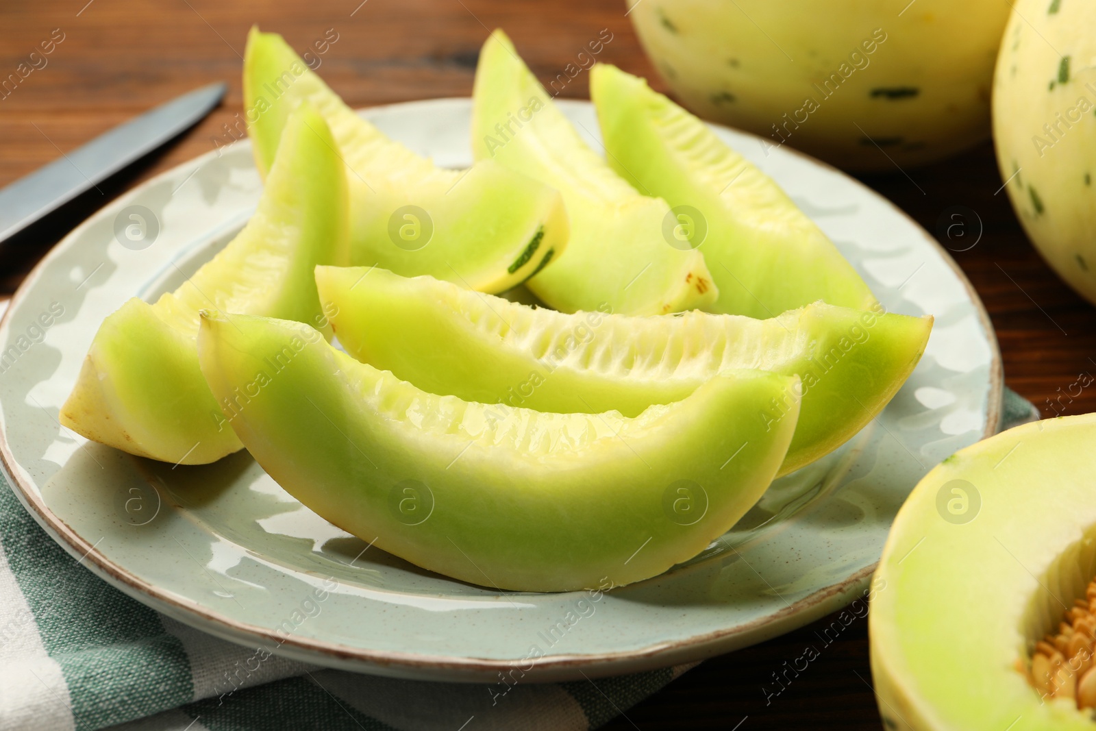 Photo of Plate with pieces of honeydew melon on wooden table, closeup