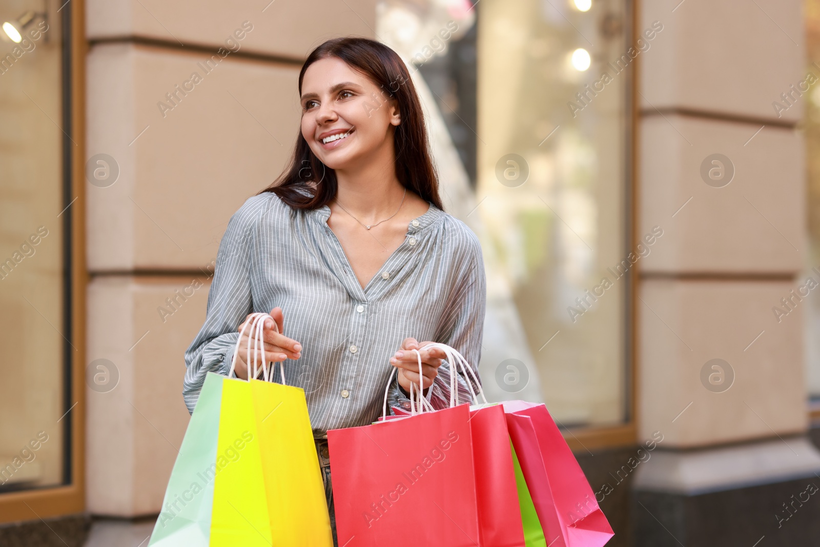 Photo of Happy woman with colorful shopping bags outdoors