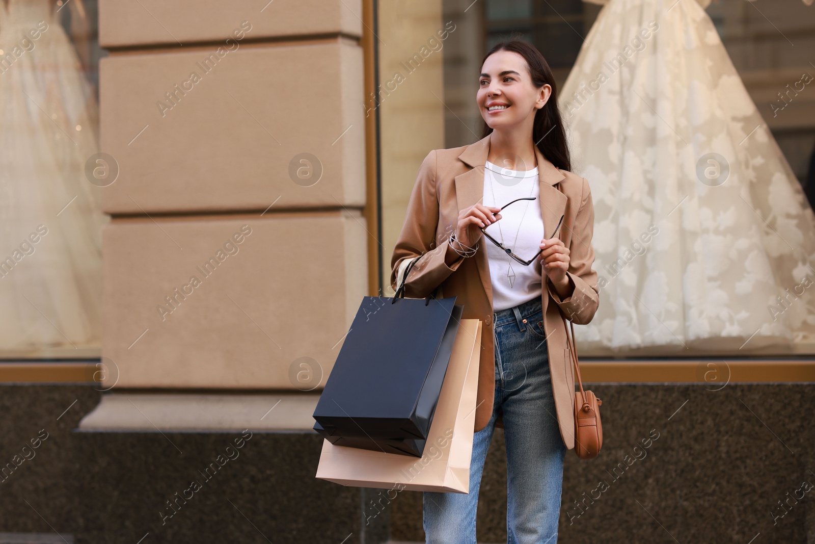 Photo of Happy woman with many shopping bags outdoors