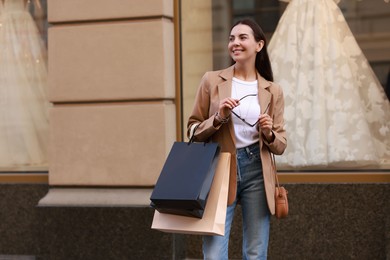 Happy woman with many shopping bags outdoors