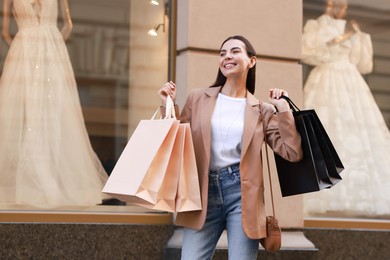 Photo of Happy woman with many shopping bags outdoors