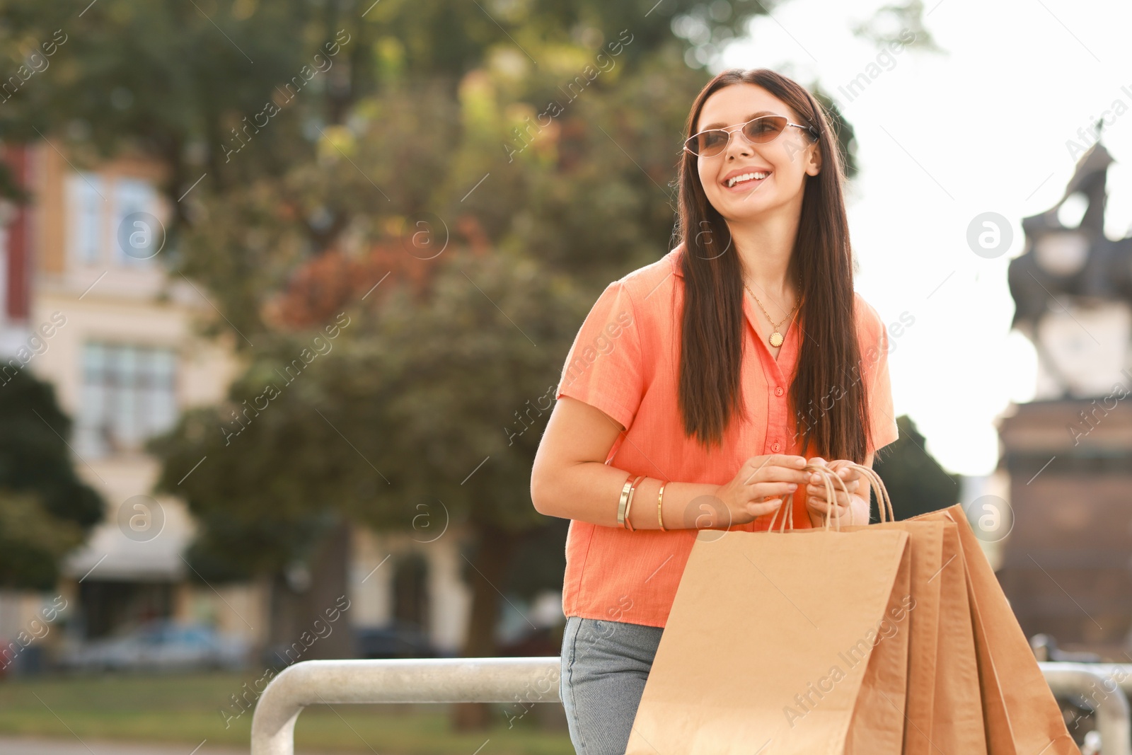 Photo of Happy woman with many shopping bags outdoors, space for text