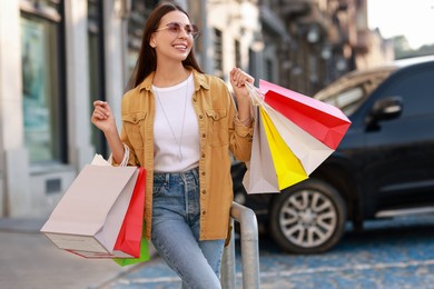 Photo of Happy woman with colorful shopping bags outdoors