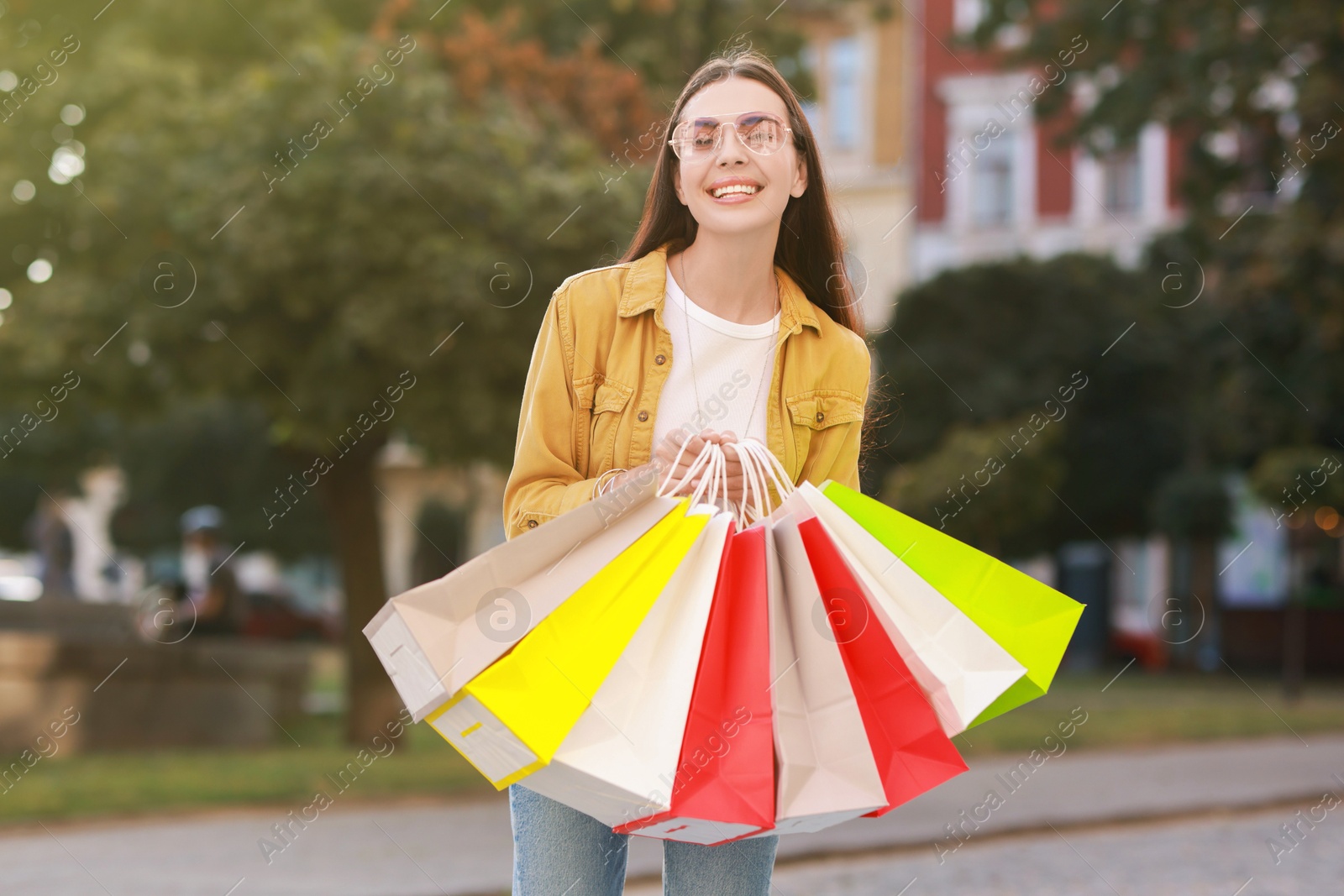 Photo of Happy woman with colorful shopping bags outdoors