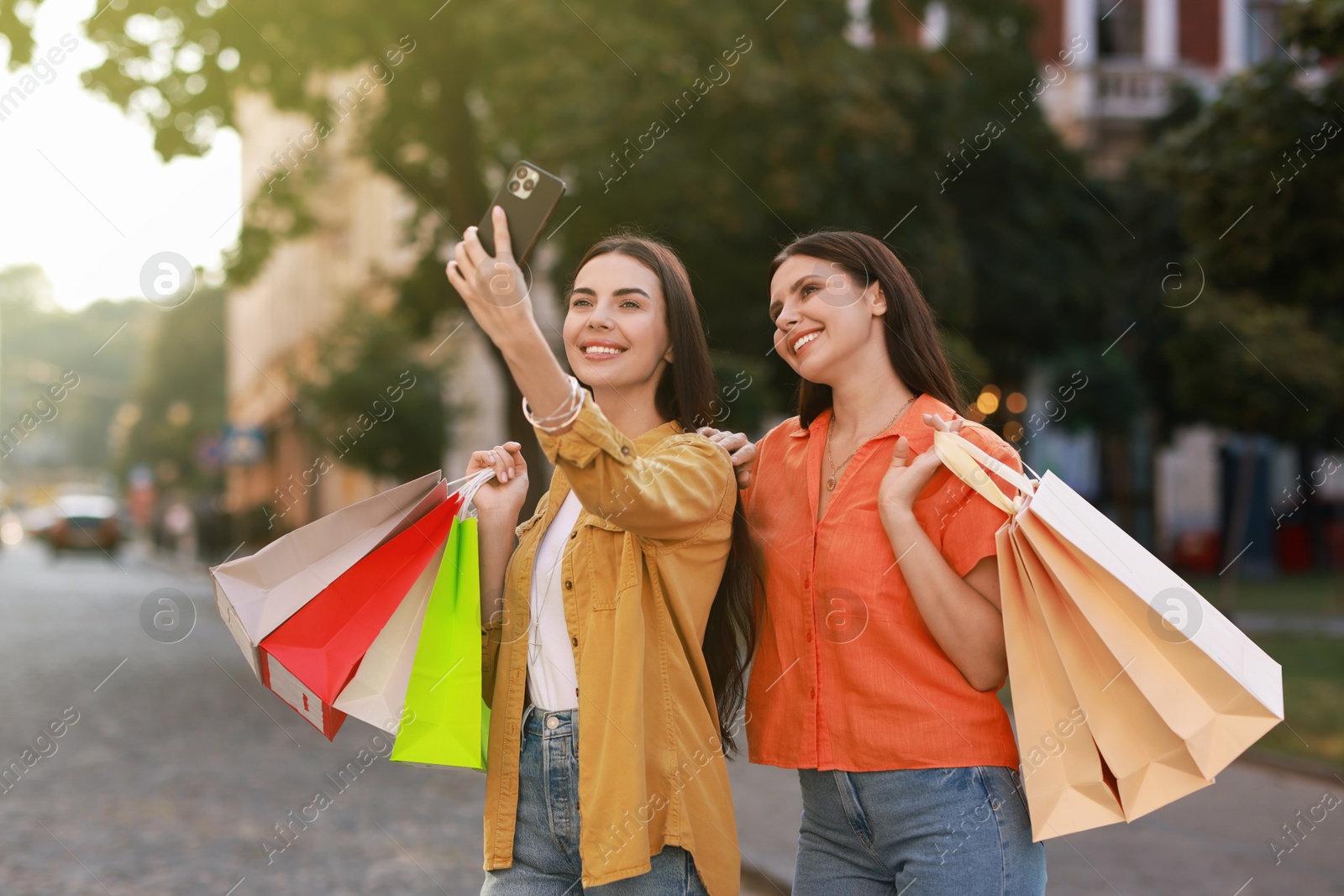 Photo of Happy women with colorful shopping bags taking selfie outdoors