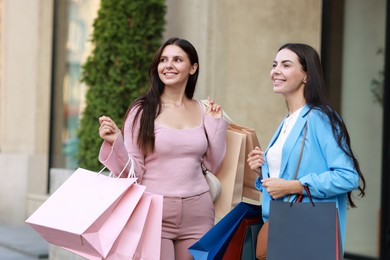 Photo of Happy women with colorful shopping bags outdoors