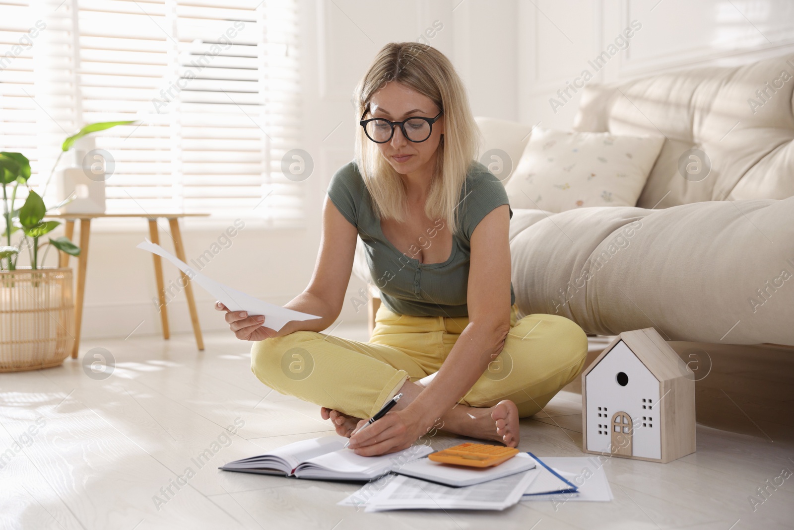 Photo of Budget planning. Woman working with accounting documents on floor indoors