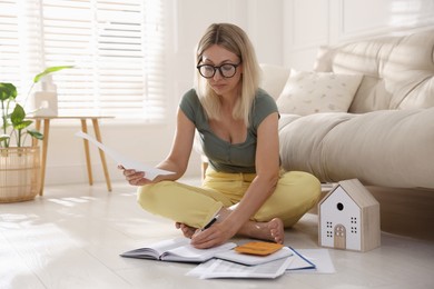 Budget planning. Woman working with accounting documents on floor indoors