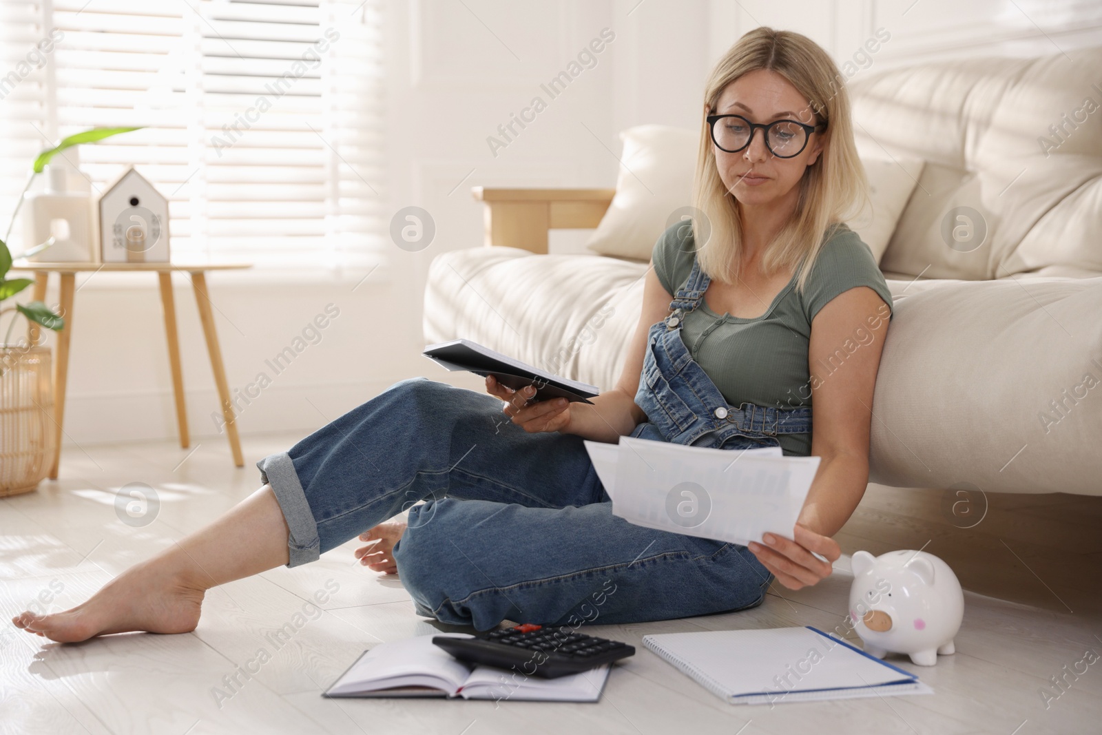 Photo of Budget planning. Woman working with accounting documents on floor indoors