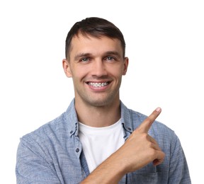 Smiling man with dental braces pointing at something on white background