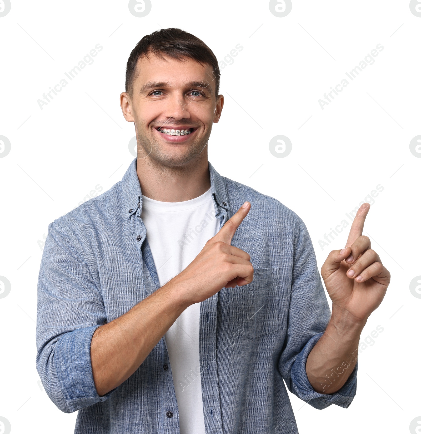 Photo of Smiling man with dental braces pointing at something on white background