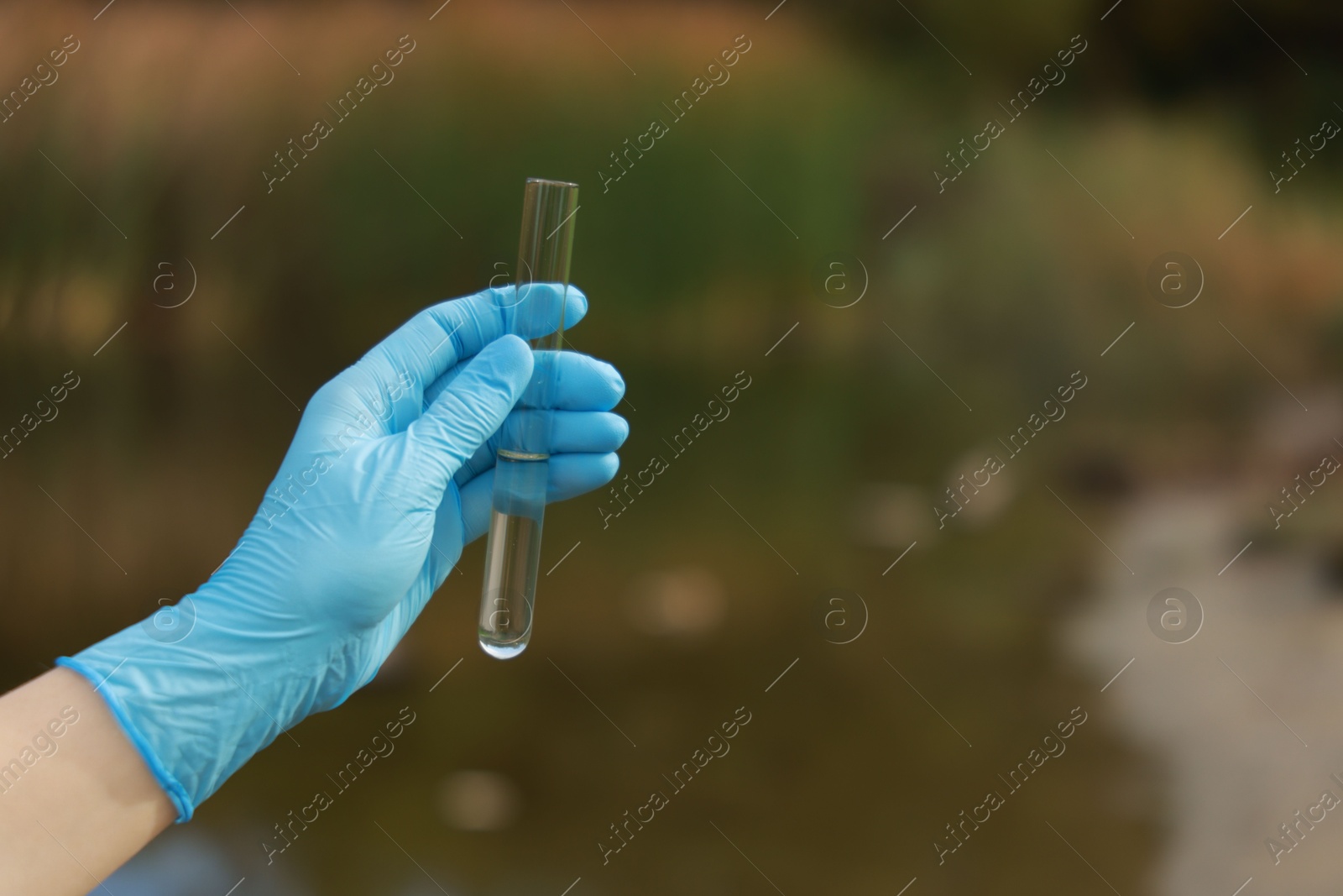 Photo of Examination of water quality. Researcher holding test tube with sample outdoors, closeup. Space for text