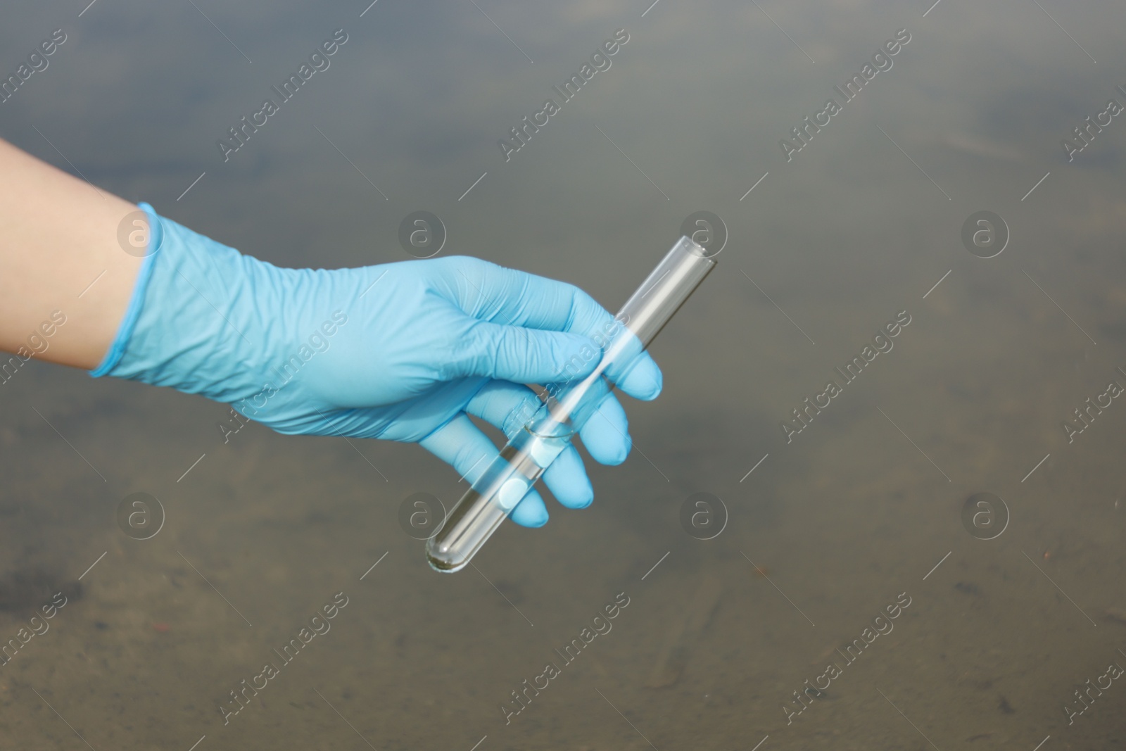 Photo of Examination of water quality. Researcher holding test tube with sample outdoors, closeup. Space for text