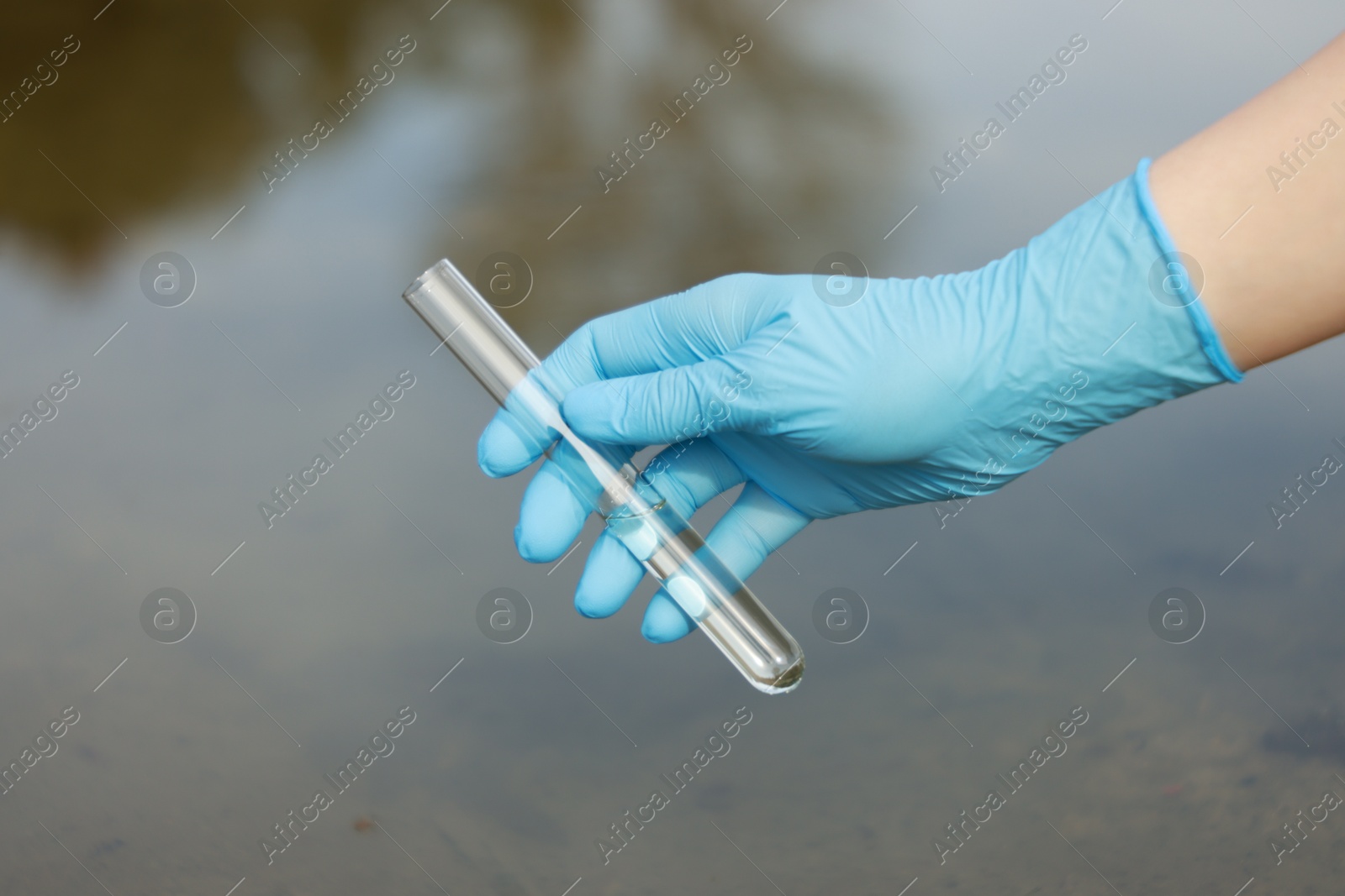 Photo of Examination of water quality. Researcher holding test tube with sample outdoors, closeup