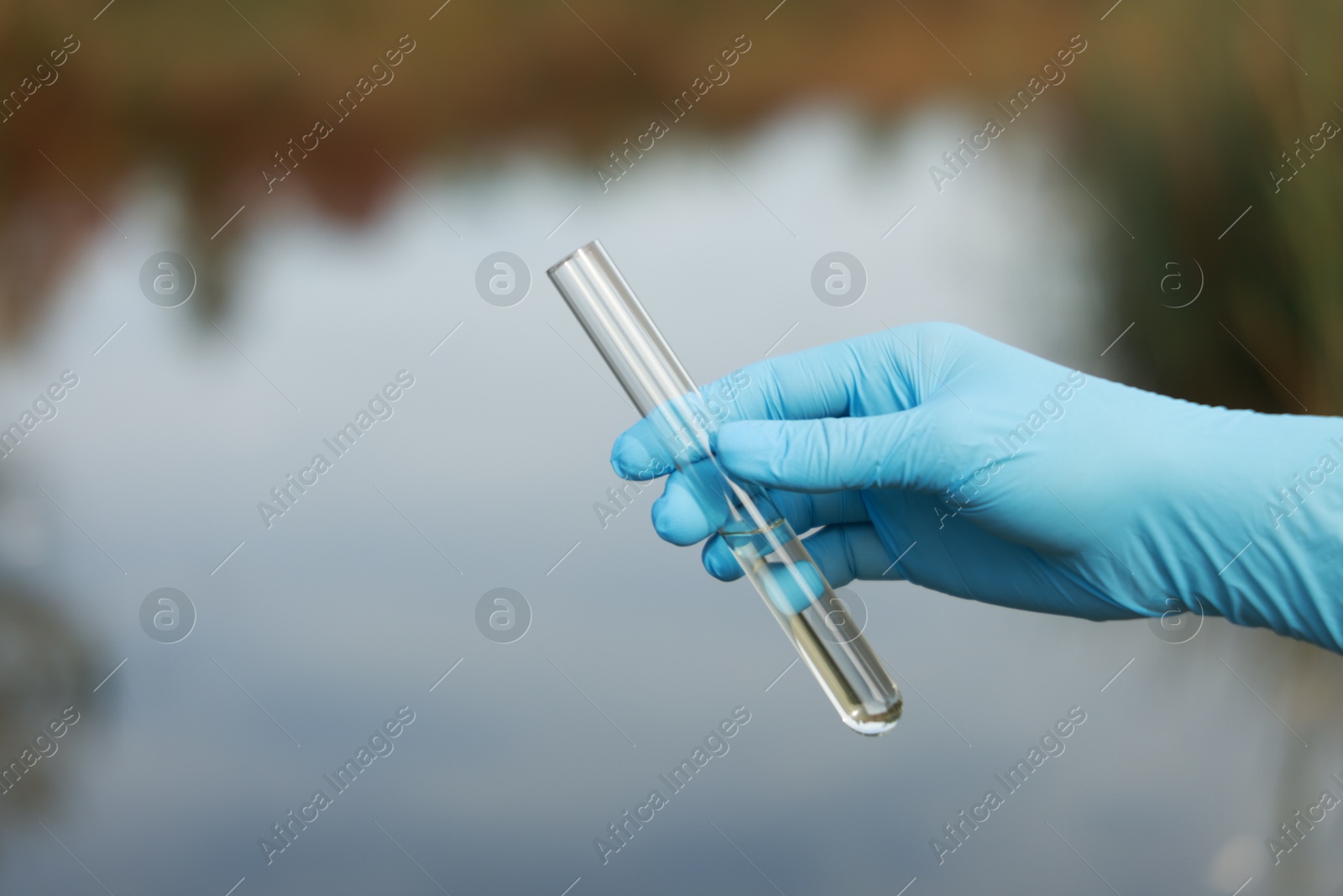 Photo of Examination of water quality. Researcher holding test tube with sample outdoors, closeup. Space for text