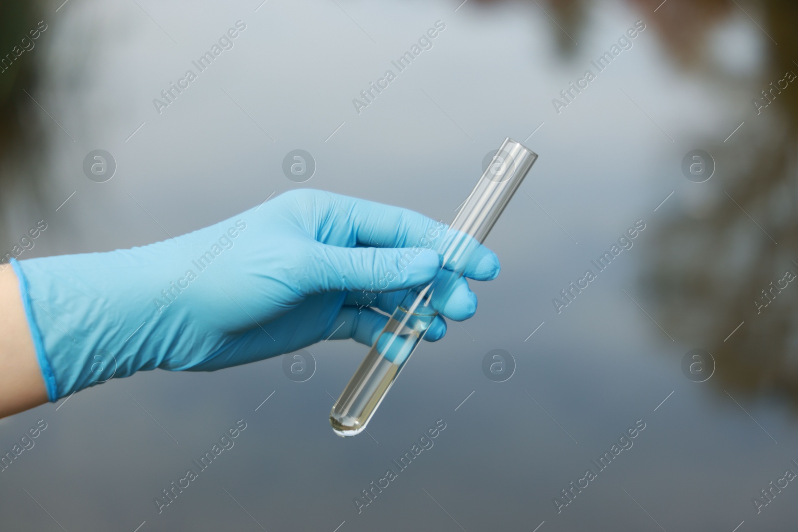 Photo of Examination of water quality. Researcher holding test tube with sample outdoors, closeup