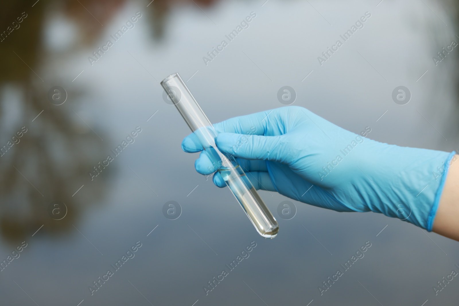 Photo of Examination of water quality. Researcher holding test tube with sample outdoors, closeup