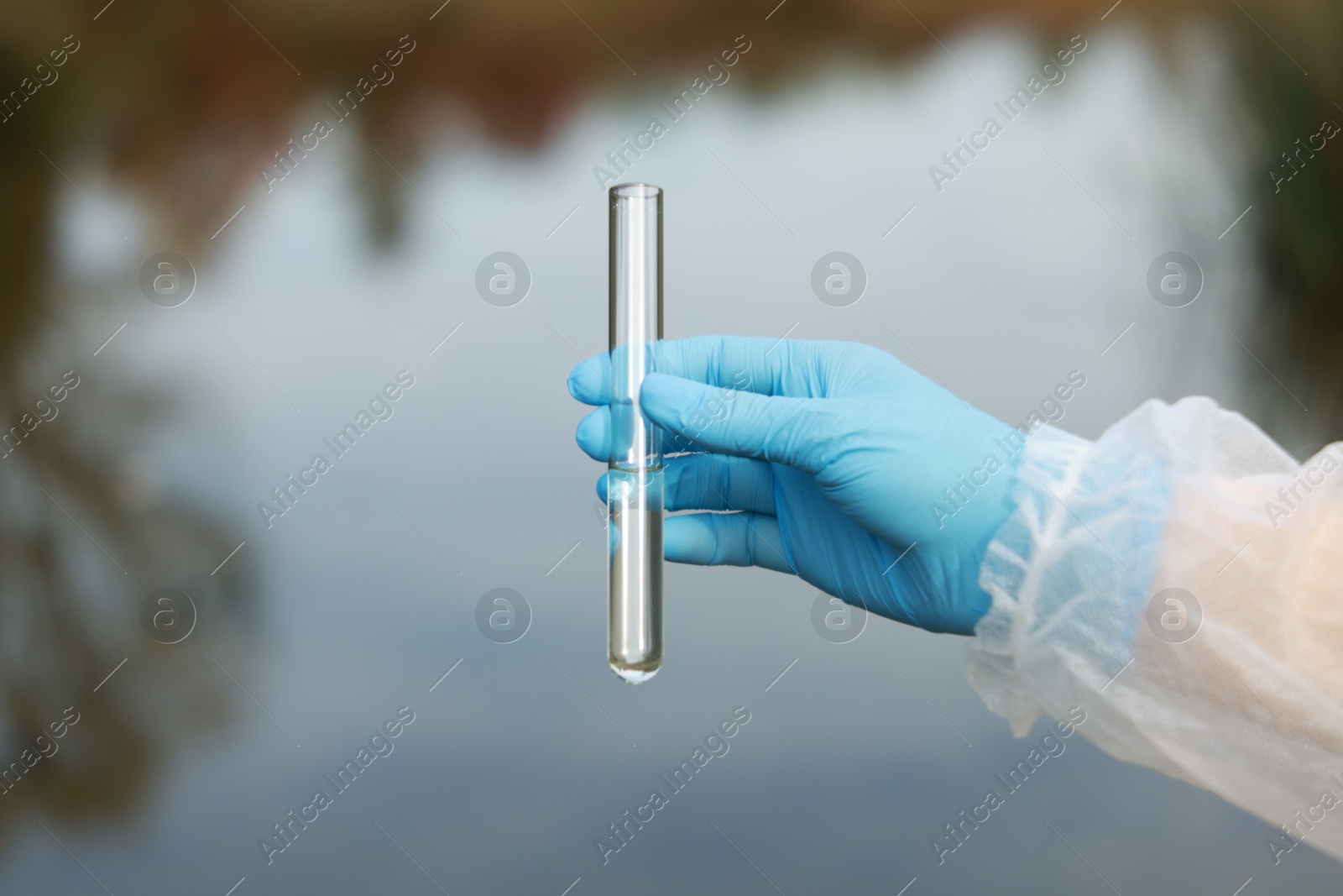 Photo of Examination of water quality. Researcher holding test tube with sample outdoors, closeup