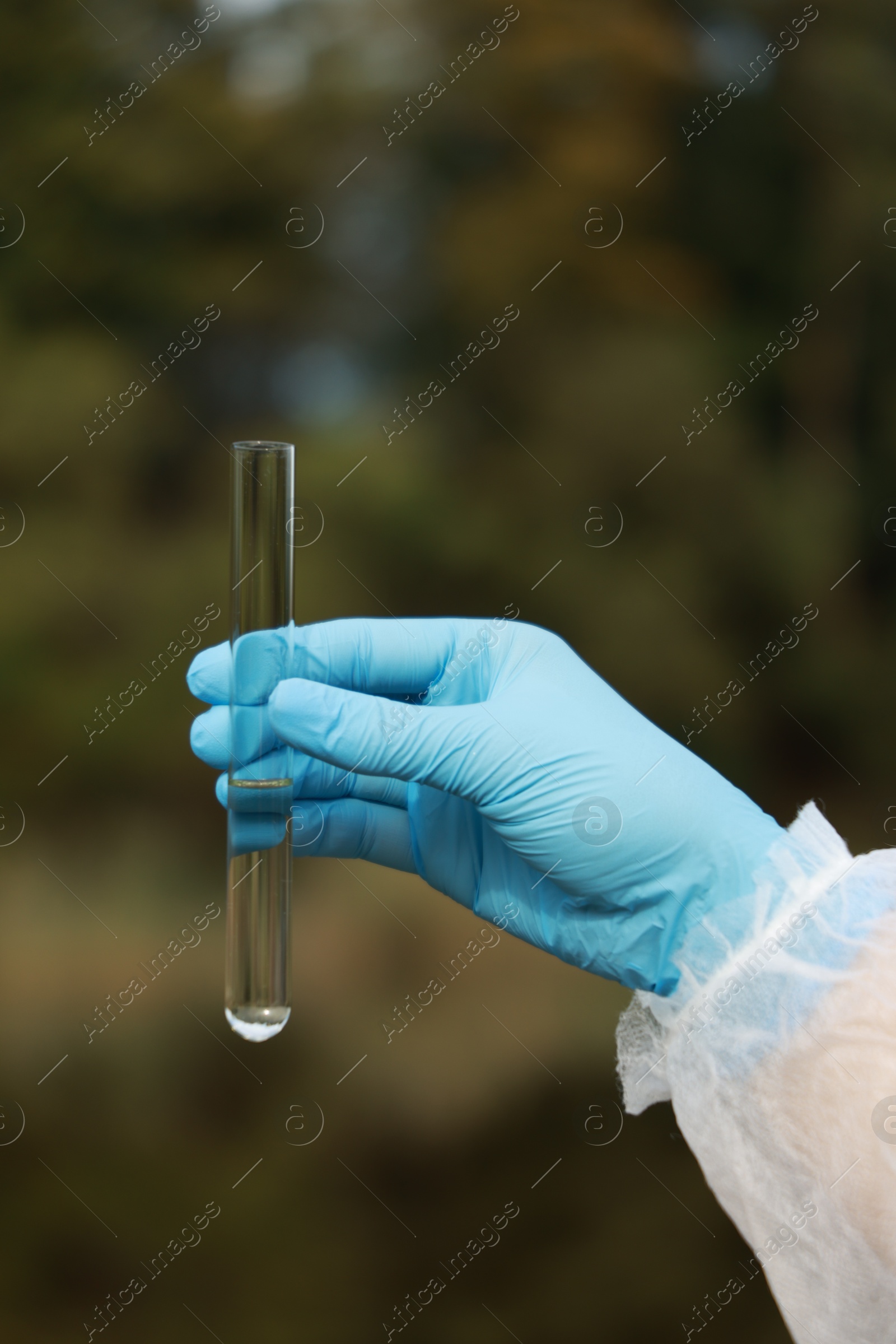 Photo of Examination of water quality. Researcher holding test tube with sample outdoors, closeup