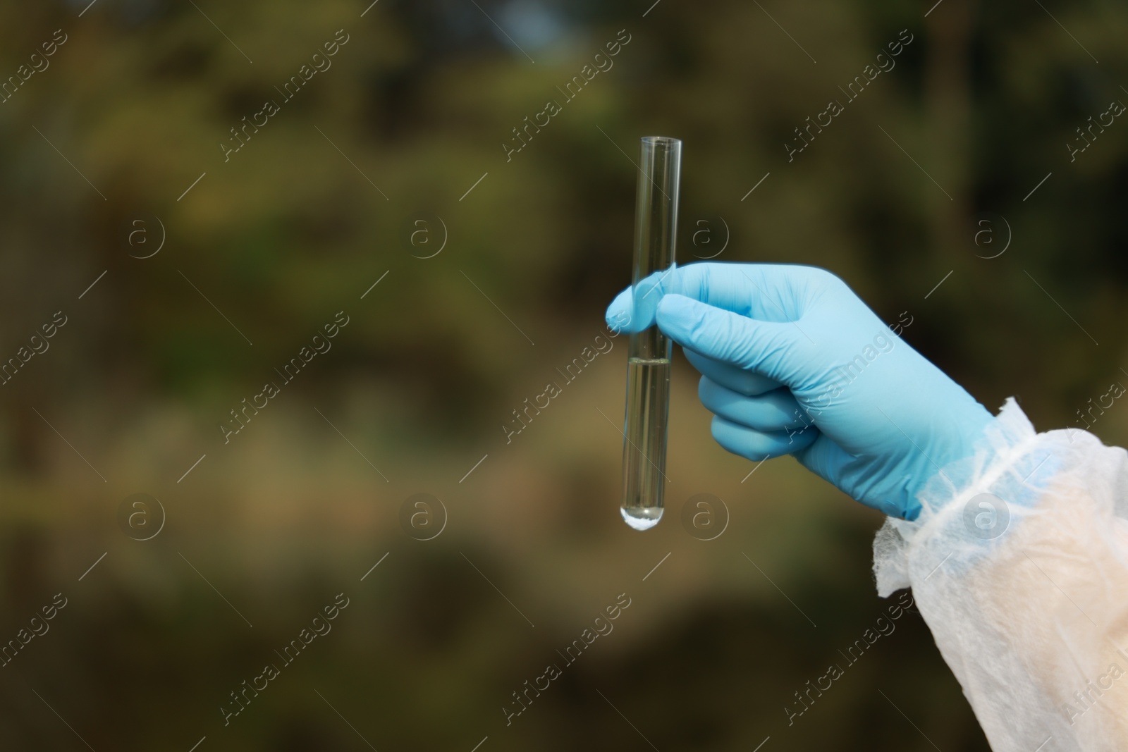 Photo of Examination of water quality. Researcher holding test tube with sample outdoors, closeup. Space for text