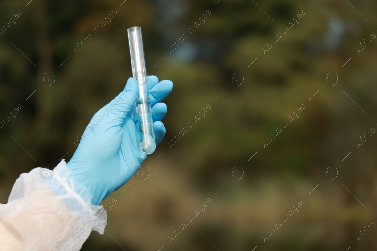 Photo of Examination of water quality. Researcher holding test tube with sample outdoors, closeup. Space for text