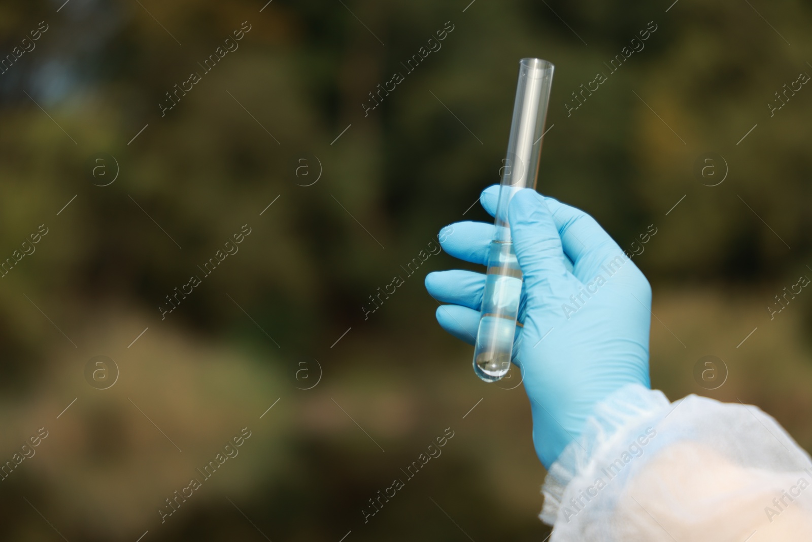 Photo of Examination of water quality. Researcher holding test tube with sample outdoors, closeup. Space for text