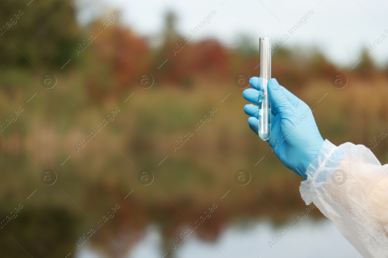 Photo of Examination of water quality. Researcher holding test tube with sample outdoors, closeup. Space for text