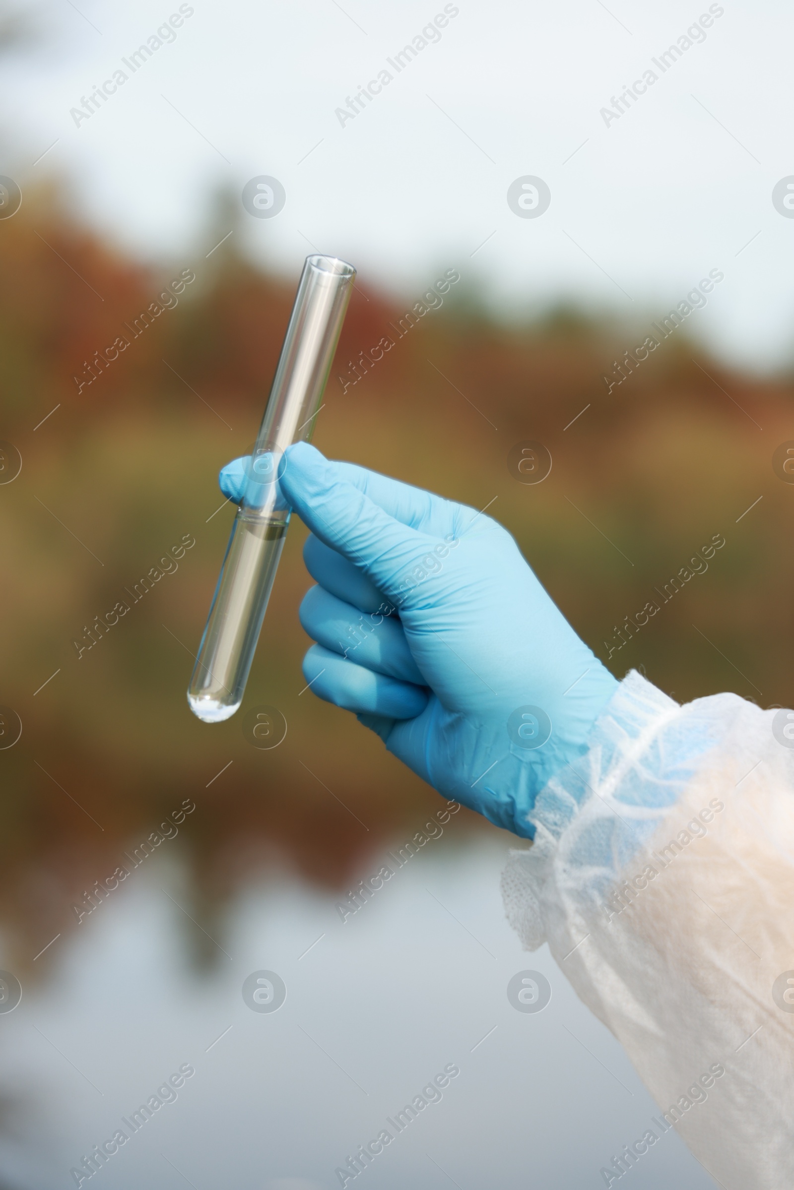 Photo of Examination of water quality. Researcher holding test tube with sample outdoors, closeup