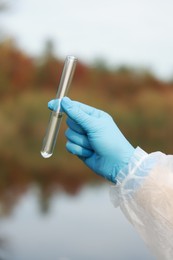 Photo of Examination of water quality. Researcher holding test tube with sample outdoors, closeup