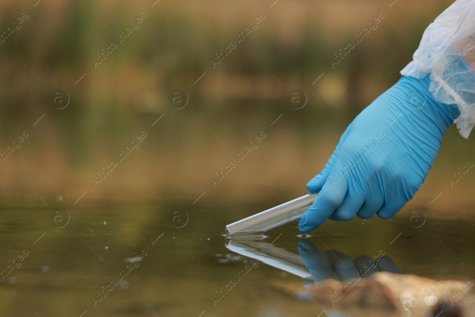 Photo of Examination of water quality. Researcher taking water sample from lake outdoors, closeup. Space for text