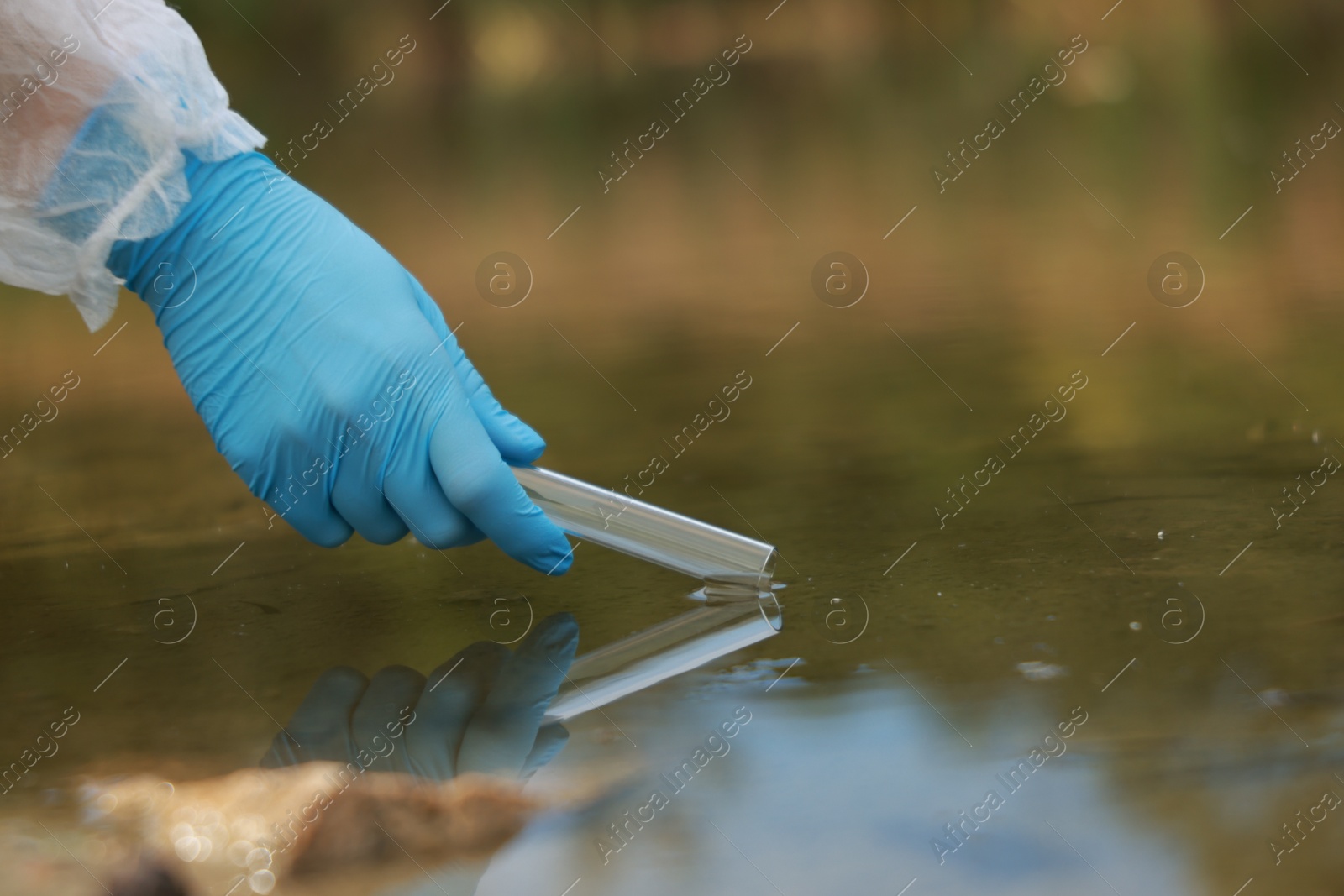 Photo of Examination of water quality. Researcher taking water sample from lake outdoors, closeup