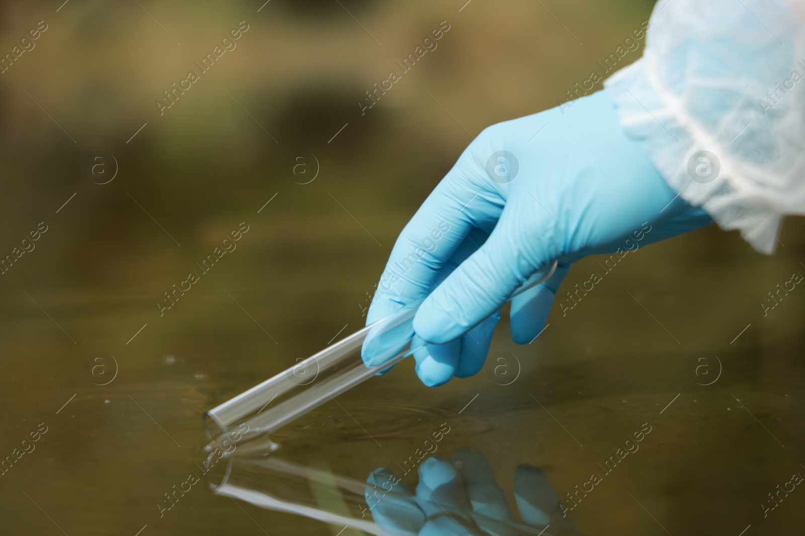 Photo of Examination of water quality. Researcher taking water sample from lake outdoors, closeup