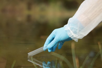 Photo of Examination of water quality. Researcher taking water sample from lake outdoors, closeup