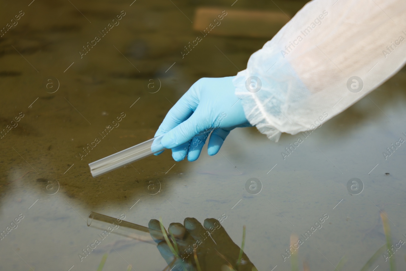 Photo of Examination of water quality. Researcher taking water sample from lake outdoors, closeup