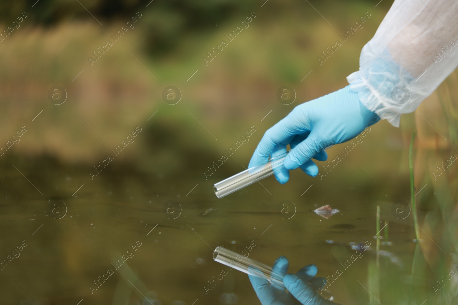 Photo of Examination of water quality. Researcher taking water sample from lake outdoors, closeup. Space for text