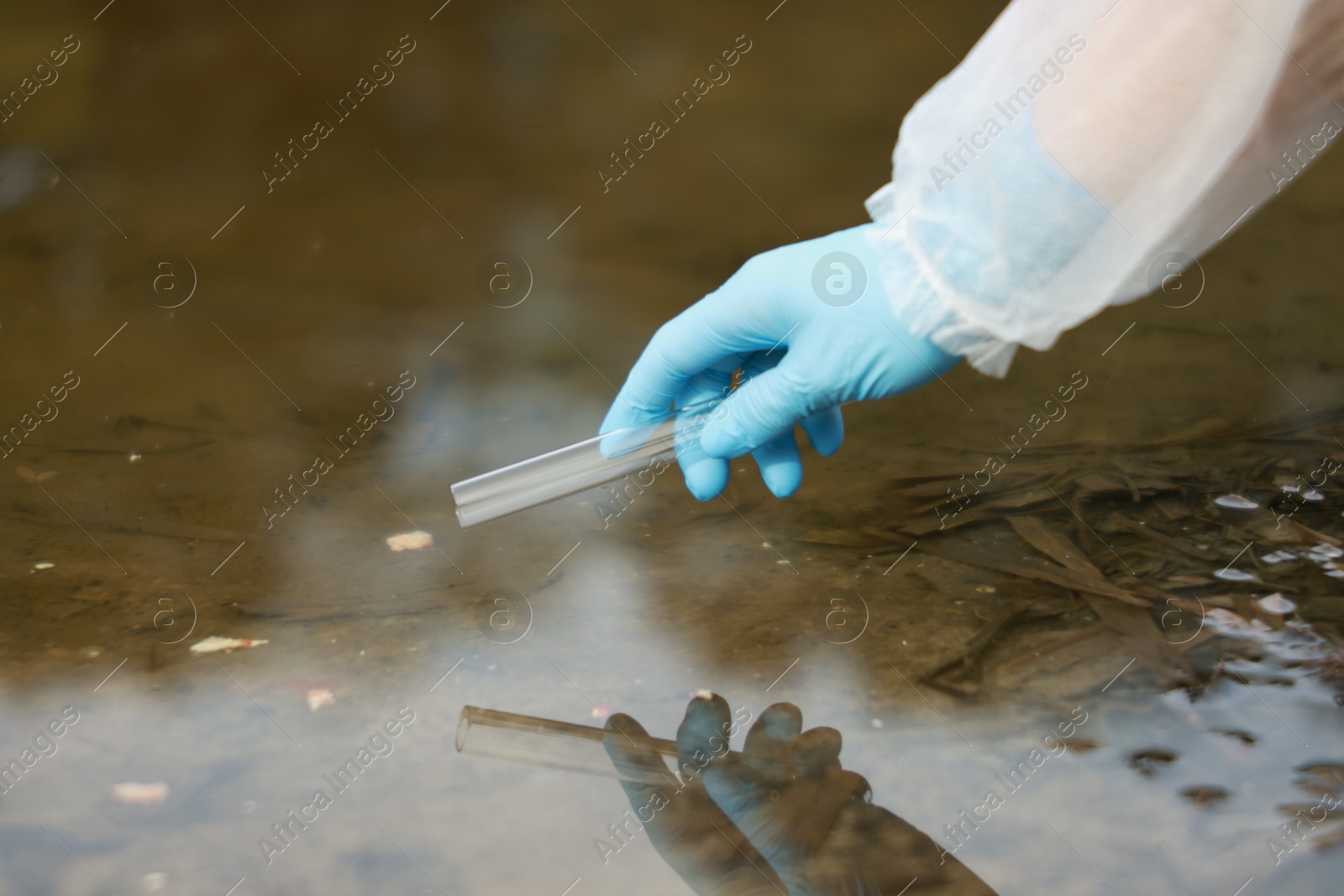 Photo of Examination of water quality. Researcher taking water sample from lake outdoors, closeup