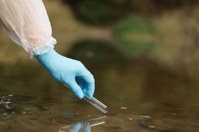 Photo of Examination of water quality. Researcher taking water sample from lake outdoors, closeup. Space for text