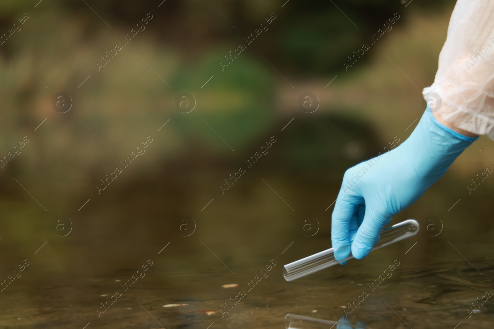 Photo of Examination of water quality. Researcher taking water sample from lake outdoors, closeup. Space for text